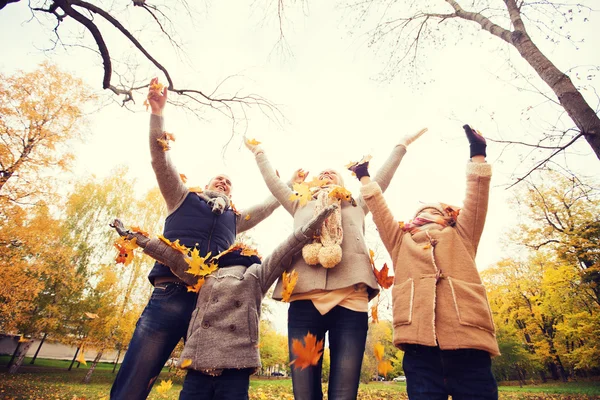 Szczęśliwa rodzina gra z jesieni pozostawia w parku — Zdjęcie stockowe