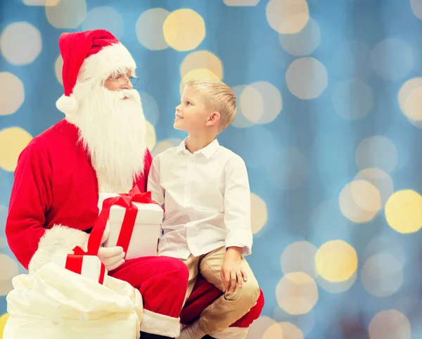 Lächelnder kleiner Junge mit Weihnachtsmann und Geschenken — Stockfoto