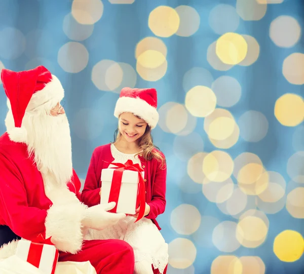 Niña sonriente con santa claus y regalos — Foto de Stock