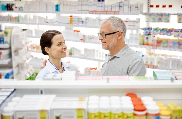 Feliz farmacéutico hablando con el hombre mayor en la farmacia — Foto de Stock