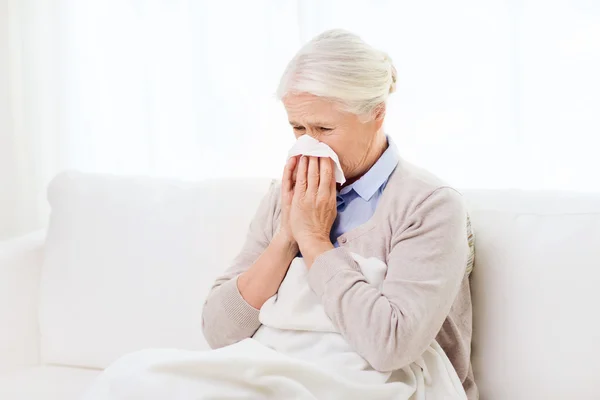 Zieke senior vrouw blazen neus aan papier servet — Stockfoto