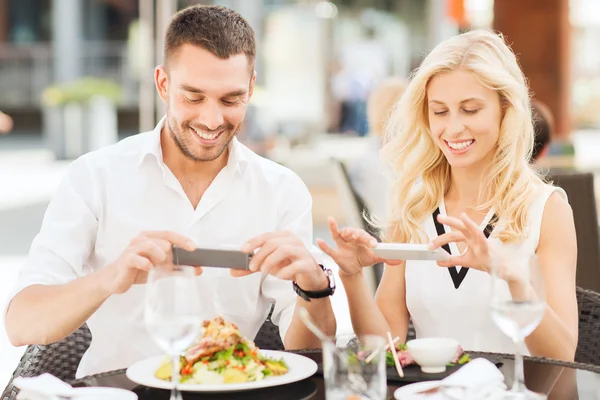 Feliz pareja con smatphone fotografiando comida —  Fotos de Stock