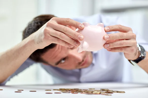 Businessman with piggy bank and coins at office Royalty Free Stock Photos