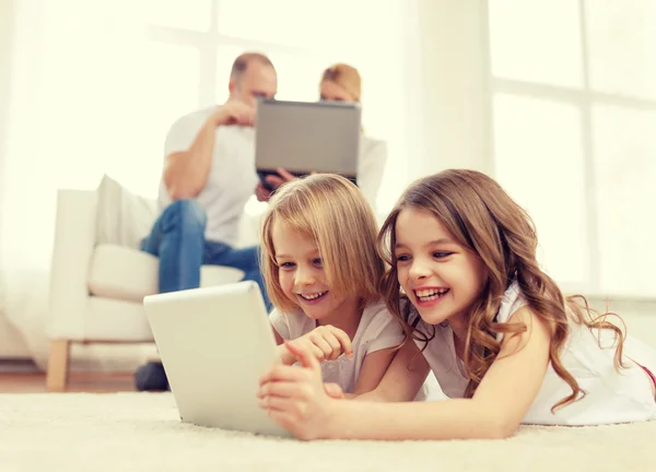 Uśmiechający się siostry z komputera typu tablet i rodziców z tyłu — Zdjęcie stockowe