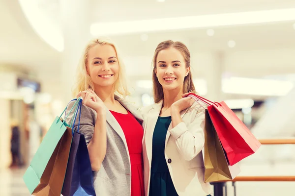 Mujeres jóvenes felices con bolsas de compras en el centro comercial — Foto de Stock