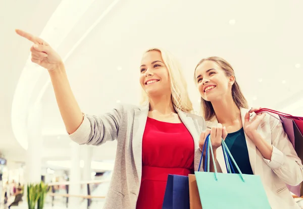 Happy young women with shopping bags in mall — Stock Photo, Image