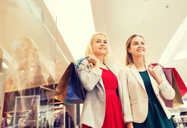 Mulheres jovens felizes com sacos de compras no shopping — Fotografia de Stock