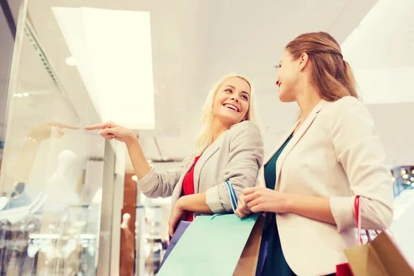 Happy young women with shopping bags in mall — Stock Photo, Image