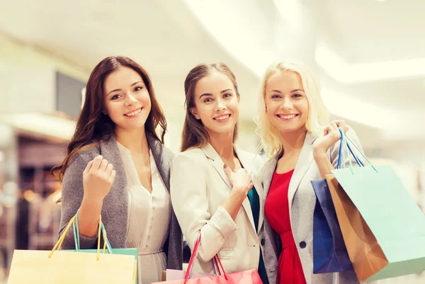 Gelukkig jonge vrouwen met boodschappentassen in winkelcentrum — Stockfoto