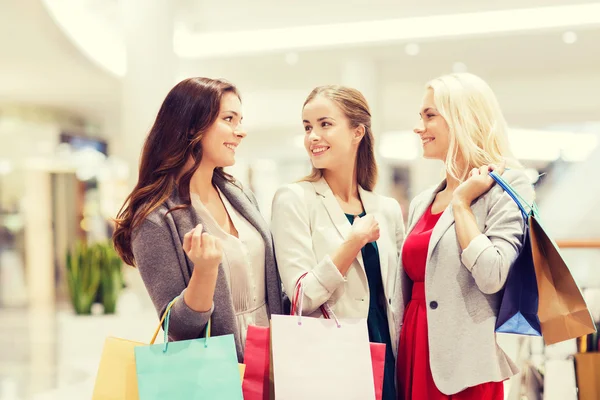 Gelukkig jonge vrouwen met boodschappentassen in winkelcentrum — Stockfoto