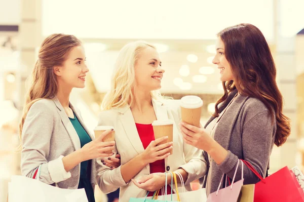 Mulheres jovens com sacos de compras e café no shopping — Fotografia de Stock