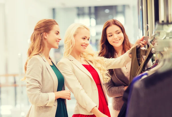 Mujeres jóvenes felices eligiendo ropa en el centro comercial —  Fotos de Stock
