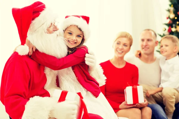 Lächelnde Familie mit Weihnachtsmann und Geschenken lizenzfreie Stockfotos