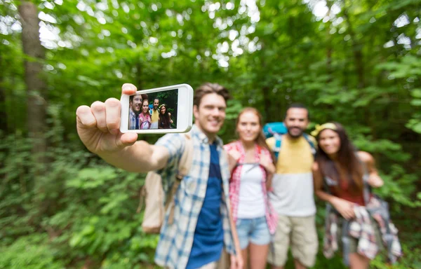 Amigos con mochilas tomando selfie por teléfono inteligente —  Fotos de Stock