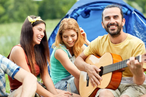 Amigos felizes com bebidas e guitarra no acampamento — Fotografia de Stock