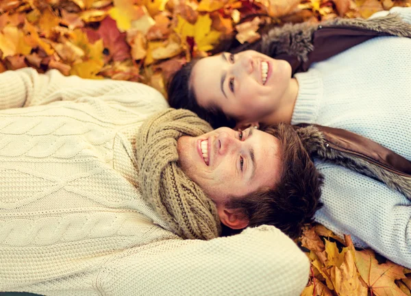 Close up of smiling couple lying in autumn park — Stock Photo, Image