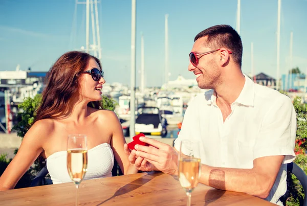 Sorrindo casal com champanhe e presente no café — Fotografia de Stock