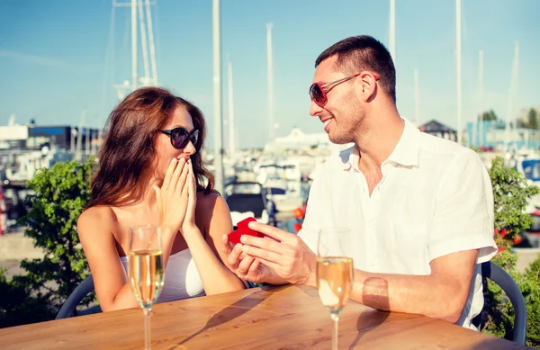 Uśmiechający się para z szampana i ofiara w kawiarni — Zdjęcie stockowe