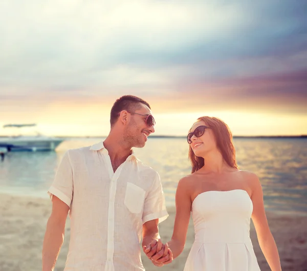 Sorrindo casal em óculos de sol andando na praia — Fotografia de Stock
