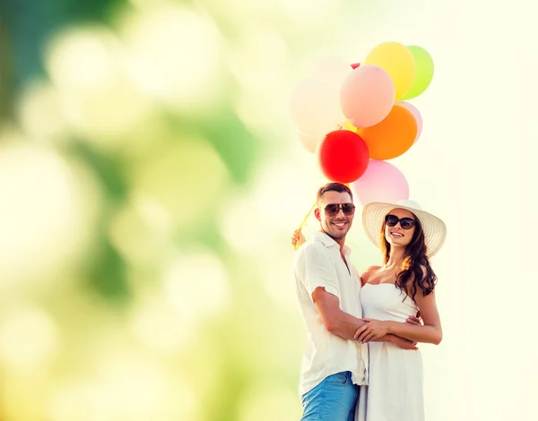 Casal sorridente com balões de ar ao ar livre — Fotografia de Stock