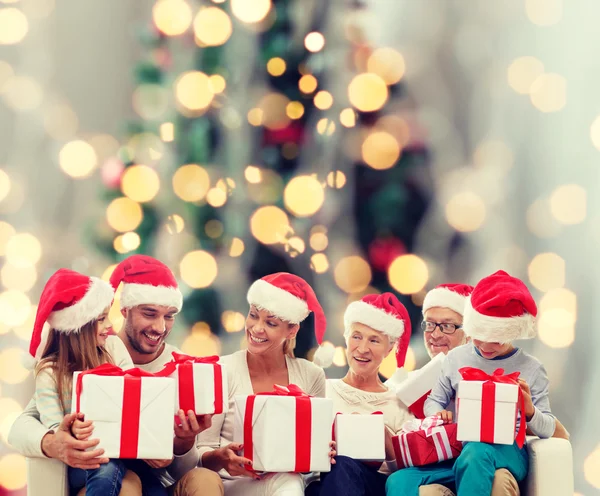 Glückliche Familie in Weihnachtsmützen mit Geschenken — Stockfoto