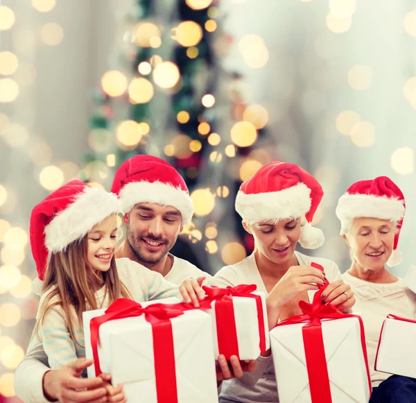 Família feliz em chapéus de santa com presentes — Fotografia de Stock