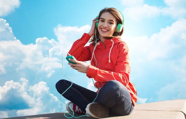 Feliz joven con teléfono inteligente y auriculares — Foto de Stock