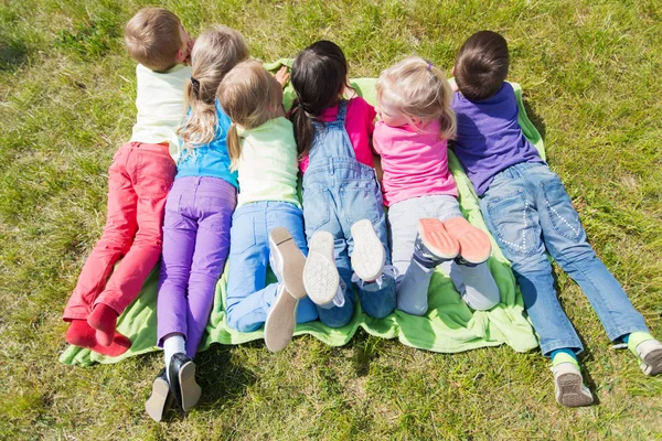 Grupo de niños acostados en una manta o cubierta al aire libre —  Fotos de Stock