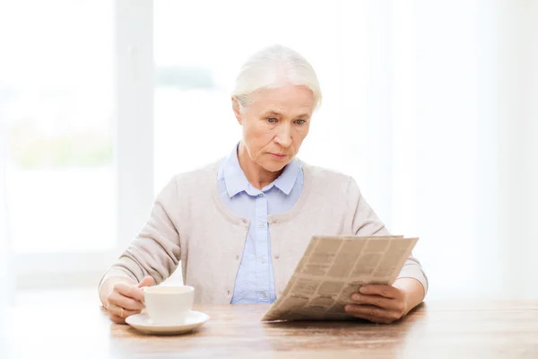 Senior woman with coffee reading newspaper — Stock Photo, Image