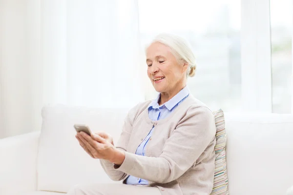 Старша жінка з смс-повідомленням смартфона вдома — стокове фото