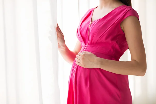 Беременная женщина смотрит в окно дома — стоковое фото