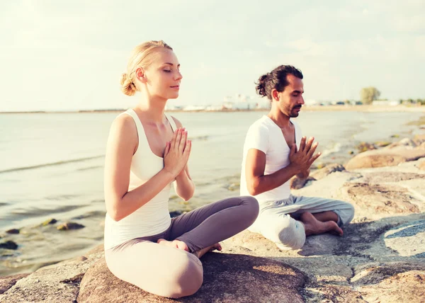 Glimlachend paar maken yoga oefeningen — Stockfoto