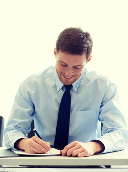 Sonriente hombre de negocios firmando papeles en la oficina — Foto de Stock