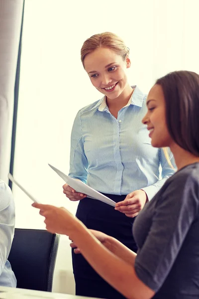 Mujeres de negocios sonrientes con papeles en la oficina — Foto de Stock