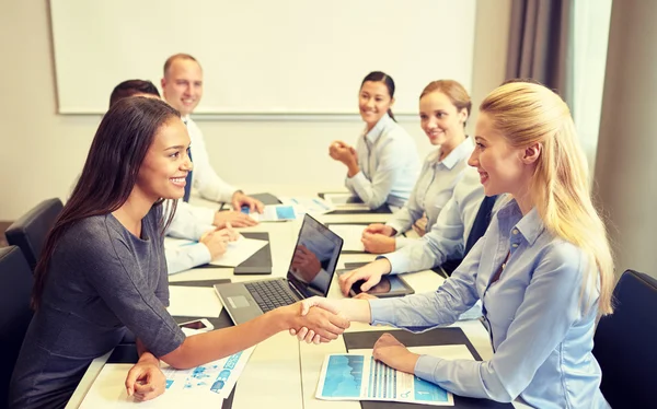 Glimlachende zakenmensen schudden handen in office — Stockfoto