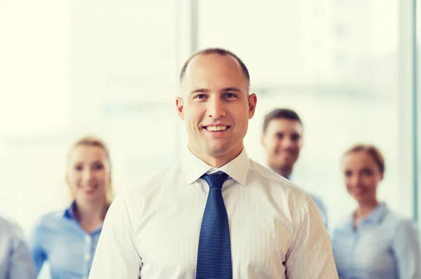 Homme d'affaires souriant avec des collègues au bureau — Photo