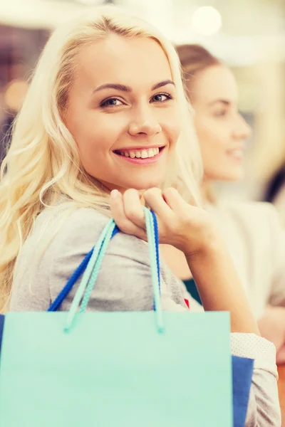 Gelukkig jonge vrouwen met boodschappentassen in winkelcentrum — Stockfoto