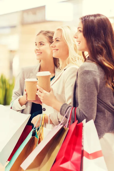 Молодые женщины с пакетами для покупок и кофе в торговом центре — стоковое фото