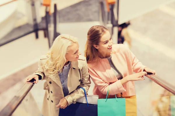 Gelukkig jonge vrouwen met boodschappentassen in winkelcentrum — Stockfoto