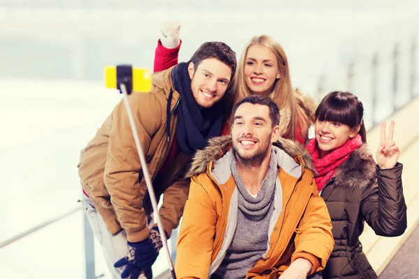 Amis heureux avec smartphone sur patinoire — Photo