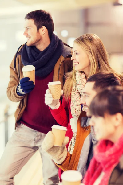 Amigos felices con tazas de café en pista de patinaje — Foto de Stock