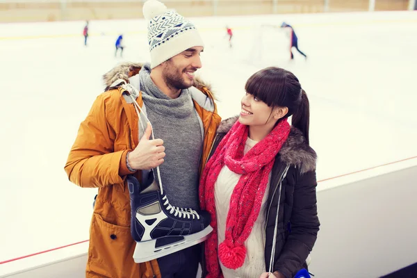 Glückliches Paar mit Schlittschuhen auf Eisbahn — Stockfoto