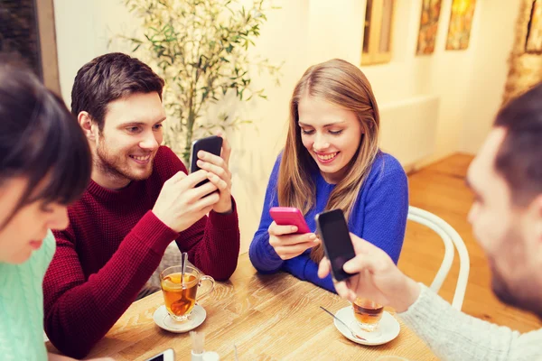 Группа друзей со смартфонами, встречающихся в кафе — стоковое фото