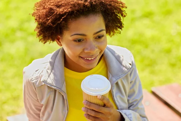 Smiling african woman drinking coffee outdoors — Stock Photo, Image