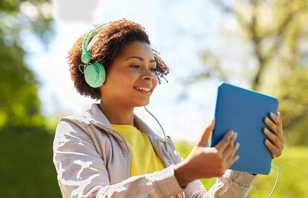 Mujer africana feliz con la PC tableta y auriculares — Foto de Stock