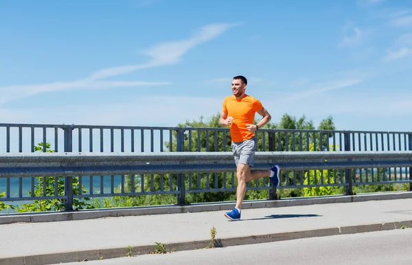 Smiling young man running at summer seaside — Stock Photo, Image