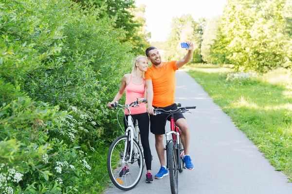 Casal com bicicleta e smartphone tirando selfie — Fotografia de Stock
