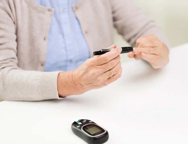 Senior woman with glucometer checking blood sugar — Stock Photo, Image