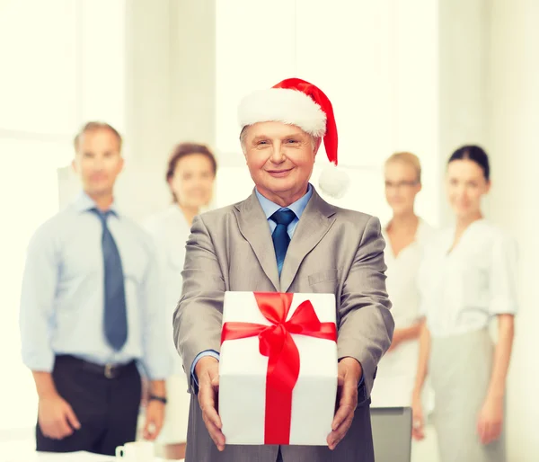 Usmívající se muž v santa hat s dárkem — Stock fotografie
