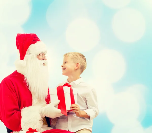 Petit garçon souriant avec santa claus et cadeaux — Photo